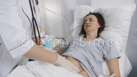 女医生带着手套在医院里摸了摸病人的腹部视频的预览图