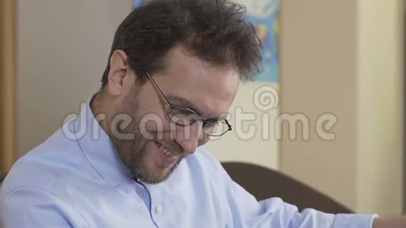40岁的快乐男坐在沙发上在报纸上看星座视频的预览图