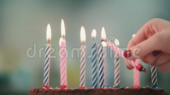 女人的手把蜡烛火焰放在生日蛋糕里在生日派对上点燃蜡烛视频的预览图