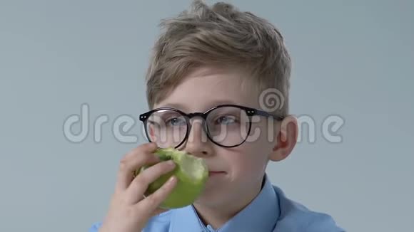 戴眼镜的有趣男孩咬绿苹果健康儿童营养维生素零食视频的预览图