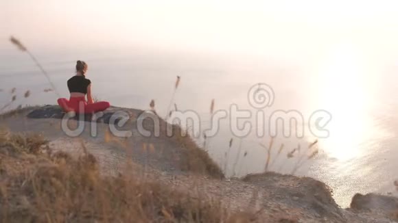 美丽的景色女人做瑜伽巴德达科纳萨纳捆绑角度在山上与海景在日落后景视频的预览图