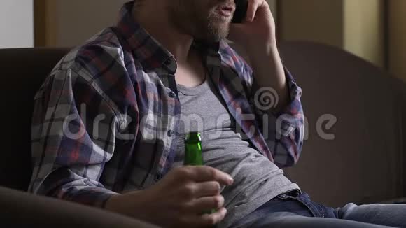 愤怒的瘾君子坐在沙发上打电话喝啤酒视频的预览图