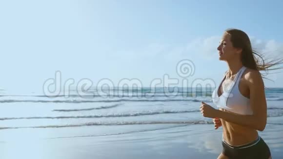 女子运动员剪影在海滩上奔跑冲刺海浪在海边的早晨背景上坠毁下面的运动步骤视频的预览图