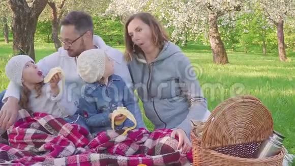 爸爸妈妈和两个女儿在野餐时唱着歌做着脸视频的预览图