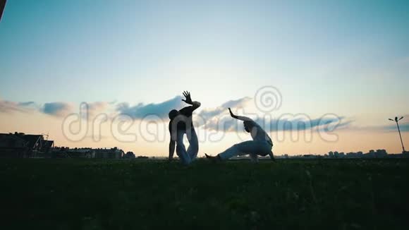 夏天的日落时分两个运动员在草地上跳秋千舞视频的预览图