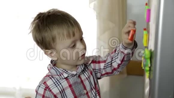 小男孩教字母表把字母放在厨房的冰箱上视频的预览图