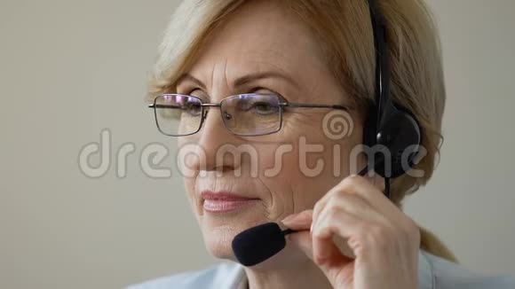 友好的微笑老妇人在耳机与客户交谈呼叫中心支持视频的预览图