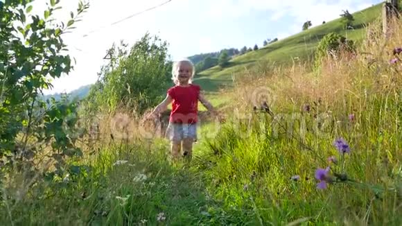 女孩沿着小路在高高的草地和野花之间奔跑视频的预览图
