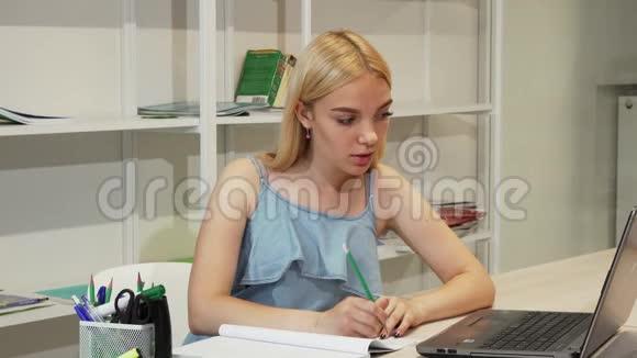 漂亮的女学生用笔记本做作业视频的预览图