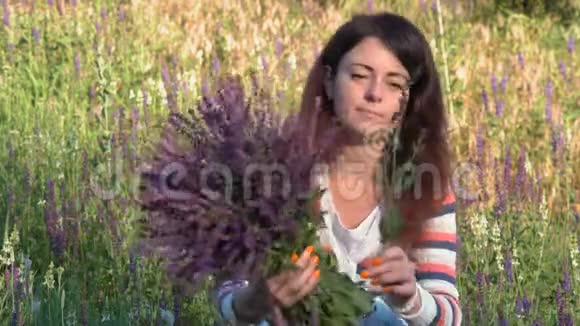 特写镜头美丽的女人在树林中的早晨聚集着山葵花束坐着跳着田野的花视频的预览图
