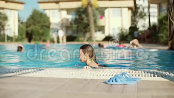 小女孩在游泳池里玩得很开心第一次学习游泳在海滩度假村度暑假视频的预览图