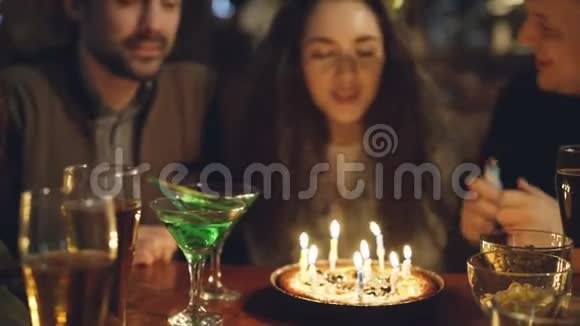 特写镜头年轻漂亮的女人吹灭生日蛋糕上的蜡烛快乐的人在笑着拍手视频的预览图