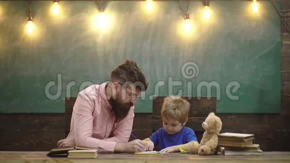 老师和小孩子在复印本上写信可爱的男孩用彩色铅笔画一幅画艺术课视频的预览图