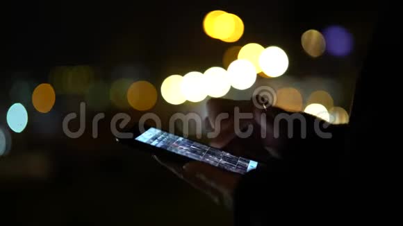 女孩手里拿着智能手机模糊了五颜六色的灯光背景关门视频的预览图