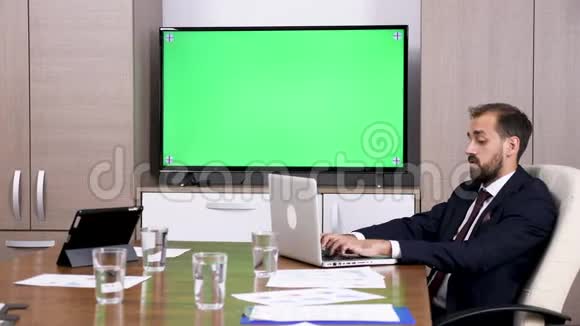 会议室里的商务人员旁边是绿色屏幕电视视频的预览图
