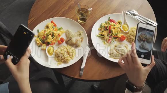 女性博客作者用手机在咖啡馆里拍下她的食物视频的预览图