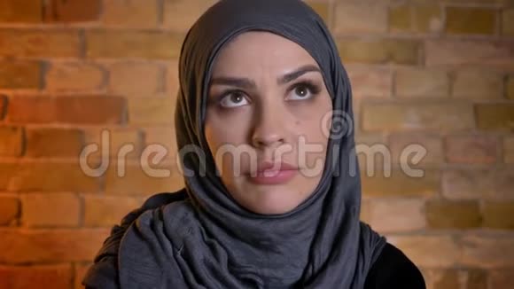戴着头巾的穆斯林成年女性在舒适的公寓里看着摄像机的特写镜头视频的预览图