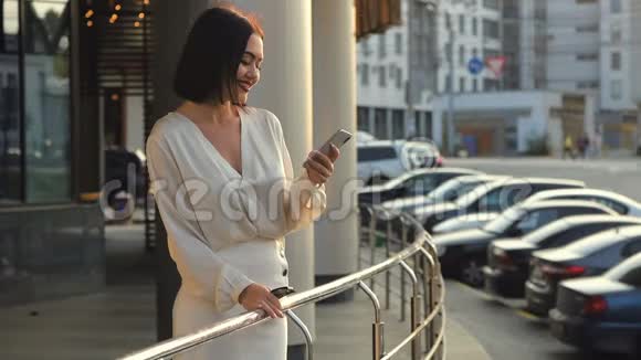 美丽优雅的商务女性步行通过城市连接使用智能手机穿白色衬衫的快乐女士视频的预览图