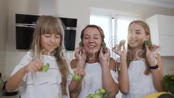 肖像有趣年轻和开朗的家庭正在厨房里玩西兰花做饭特写镜头吸引力视频的预览图