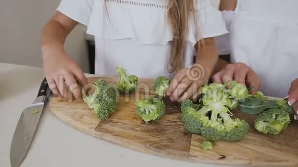 小女孩和她的母亲在雕刻板上切鲜花椰菜女性用切片的特写镜头视频的预览图