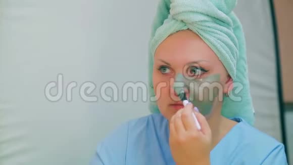 洗澡后的一个年轻女人用刷子把一个泥面具涂在脸上视频的预览图