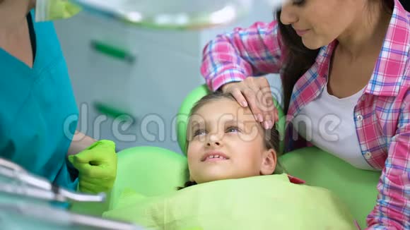 孩子害怕牙科检查医生和父母安抚小女孩视频的预览图