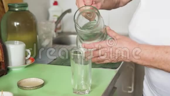一个老妇人把水从一个衰人灌入一个玻璃视频的预览图
