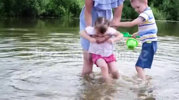 小女孩的母亲在河里洗脚一个女人和她的孩子站在水里视频的预览图