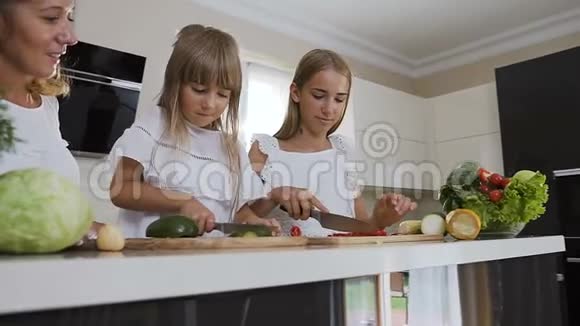 妈妈和两个女儿在厨房做饭十几岁的女孩切红辣椒妹妹切熟视频的预览图