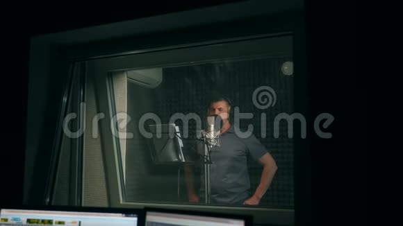 男歌手戴着耳机唱着歌进入录音室的麦克风展示商业理念一名成年男子录制视频的预览图