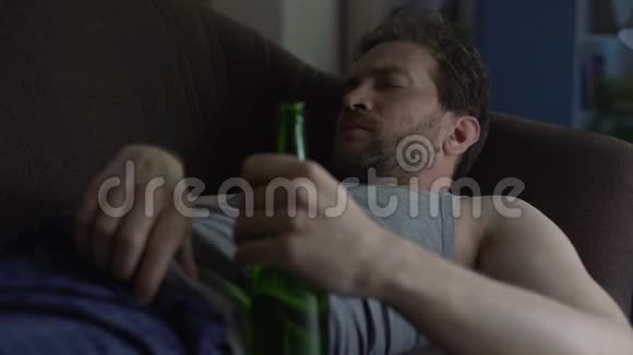 成年人睡在沙发上拿着啤酒瓶打哈欠和抓肚视频的预览图