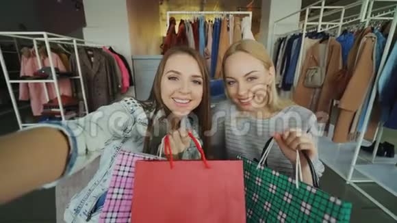 观点拍摄两个迷人的粗心女孩自拍与纸袋在妇女服装店是朋友视频的预览图