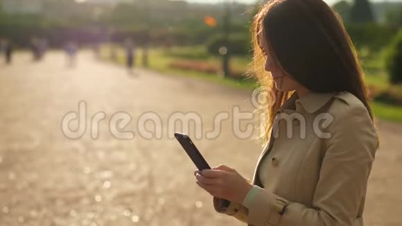 有智能手机的女人站在阳光下视频的预览图