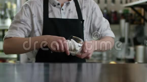 男酒保正在用干餐巾纸擦拭酒吧背景上的湿玻璃酒保在柜台附近擦玻璃视频的预览图