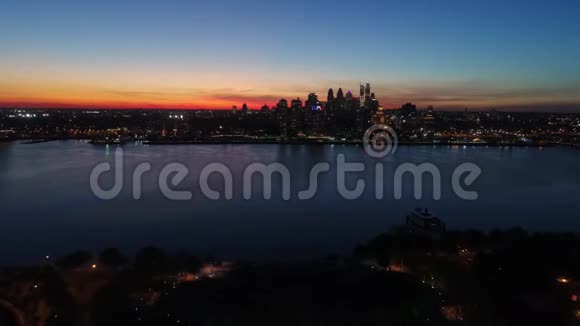 迷人的4k空中无人机在明亮的橙色傍晚日落天空上的黑暗灯光城市费城海洋海景视频的预览图