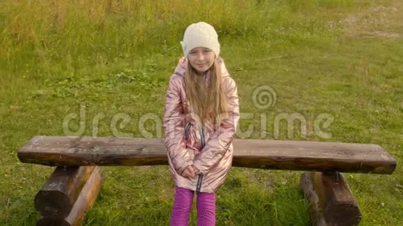 可爱的不幸女孩坐在草地上的木凳上视频的预览图