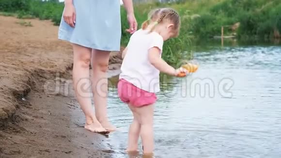 小孩子在河里玩夏天女孩从锅里倒水妈妈照顾她的女儿视频的预览图