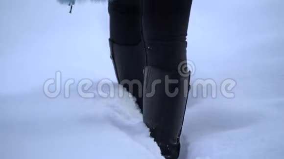 女孩走在白雪皑皑的冬林里腿部特写深雪中的靴子在雪地里台阶慢动作视频的预览图