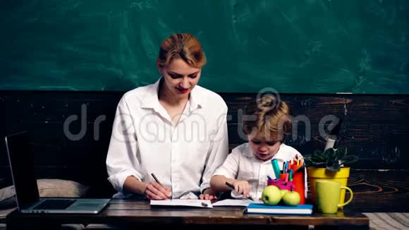 一个穿着白色衬衫的男孩和母亲被画在绿色木板的背景上学习观念学龄儿童视频的预览图