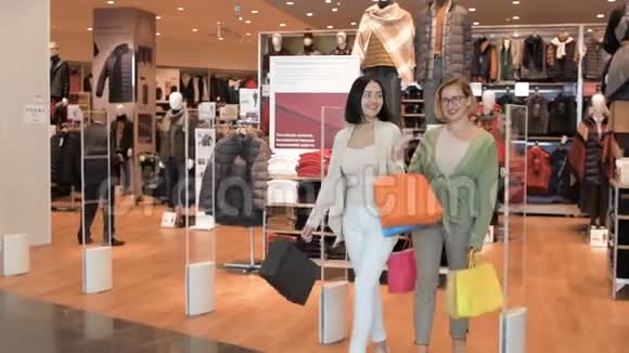 快乐微笑的女人带着袋子从服装店出来女朋友从商场的奢侈品店门口走视频的预览图