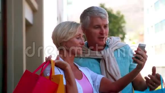 快乐的一对情侣在外面购物看智能手机视频的预览图
