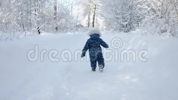 穿着冬装的小男孩在白雪覆盖的小路上奔跑视频的预览图
