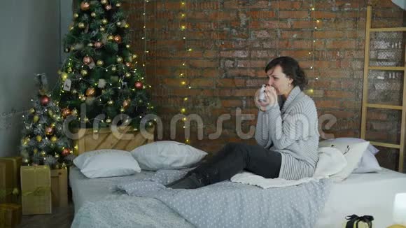 在圣诞树附近喝热茶的女人视频的预览图