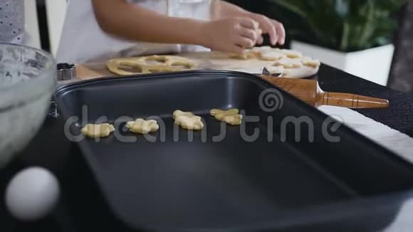 小女孩把一块生饼干放在烤盘上孩子和他的母亲一起在家里烤饼干饼干视频的预览图