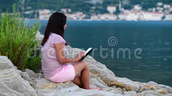 美丽的年轻女孩在海边读碑文和梦想视频的预览图