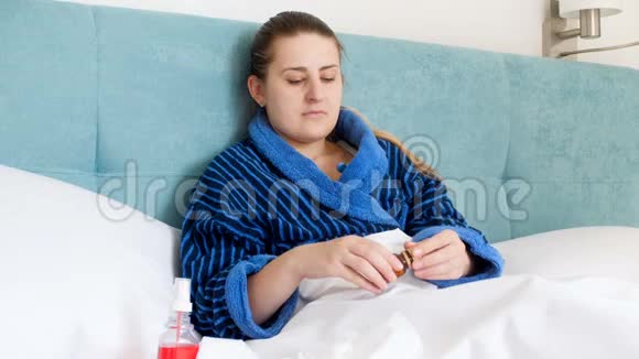 4k视频穿着浴袍的年轻女子躺在床上喝药视频的预览图