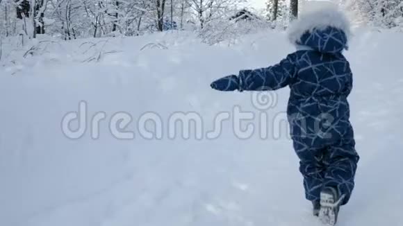 穿着冬装的小男孩在白雪覆盖的小路上奔跑视频的预览图