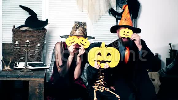 万圣节派对和庆祝理念巫师女巫和小骨架把他们的脸藏在南瓜后面家庭视频的预览图