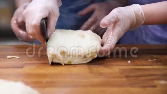 女人在烹饪手套切割膨化糕点与葡萄干成片食品概念库存录像双手合拢视频的预览图