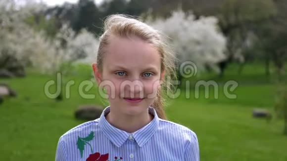 描绘春天站在公园里的蓝眼睛白种人的小女孩视频的预览图